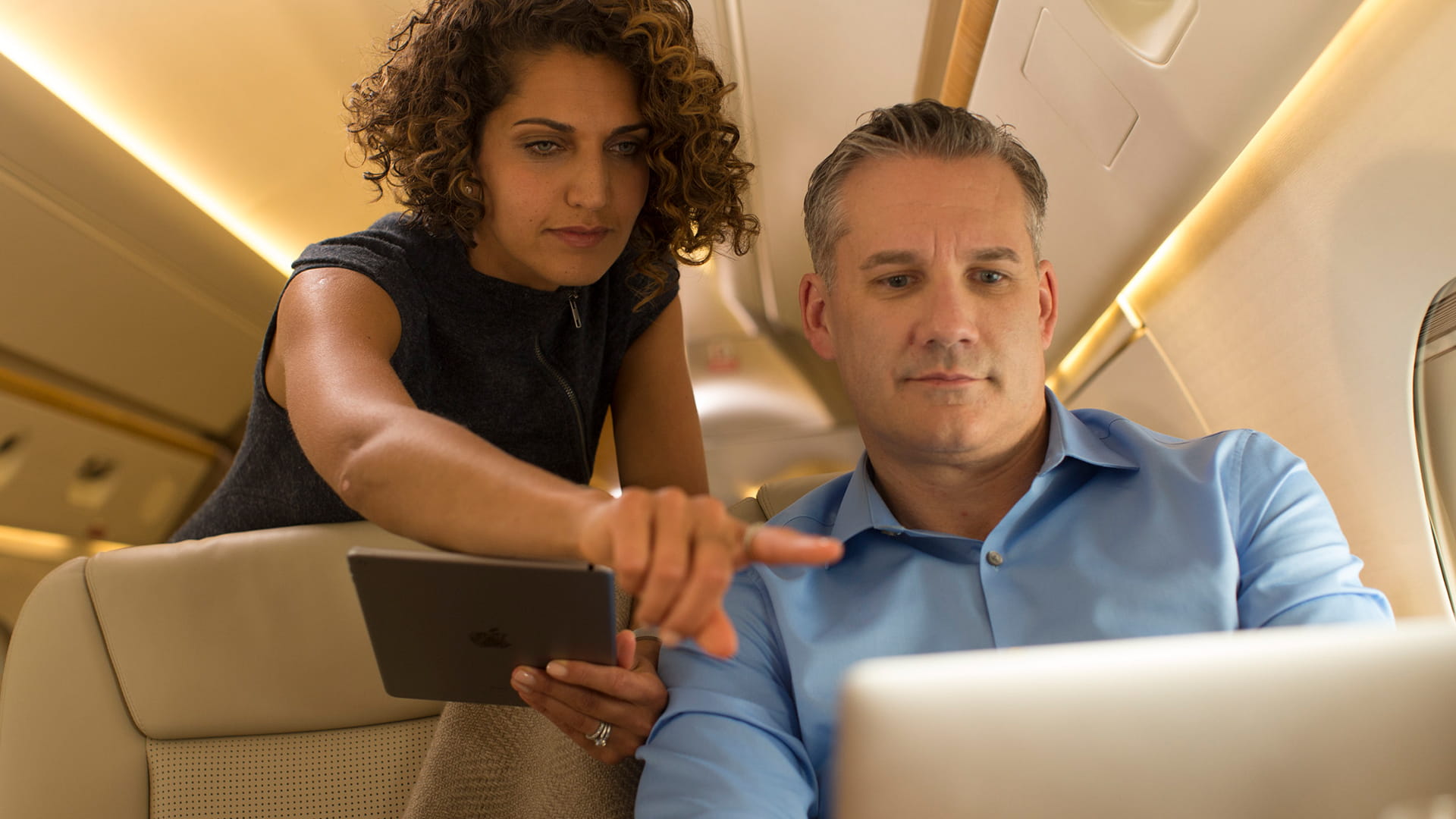 Woman pointing at screen in jet cabin