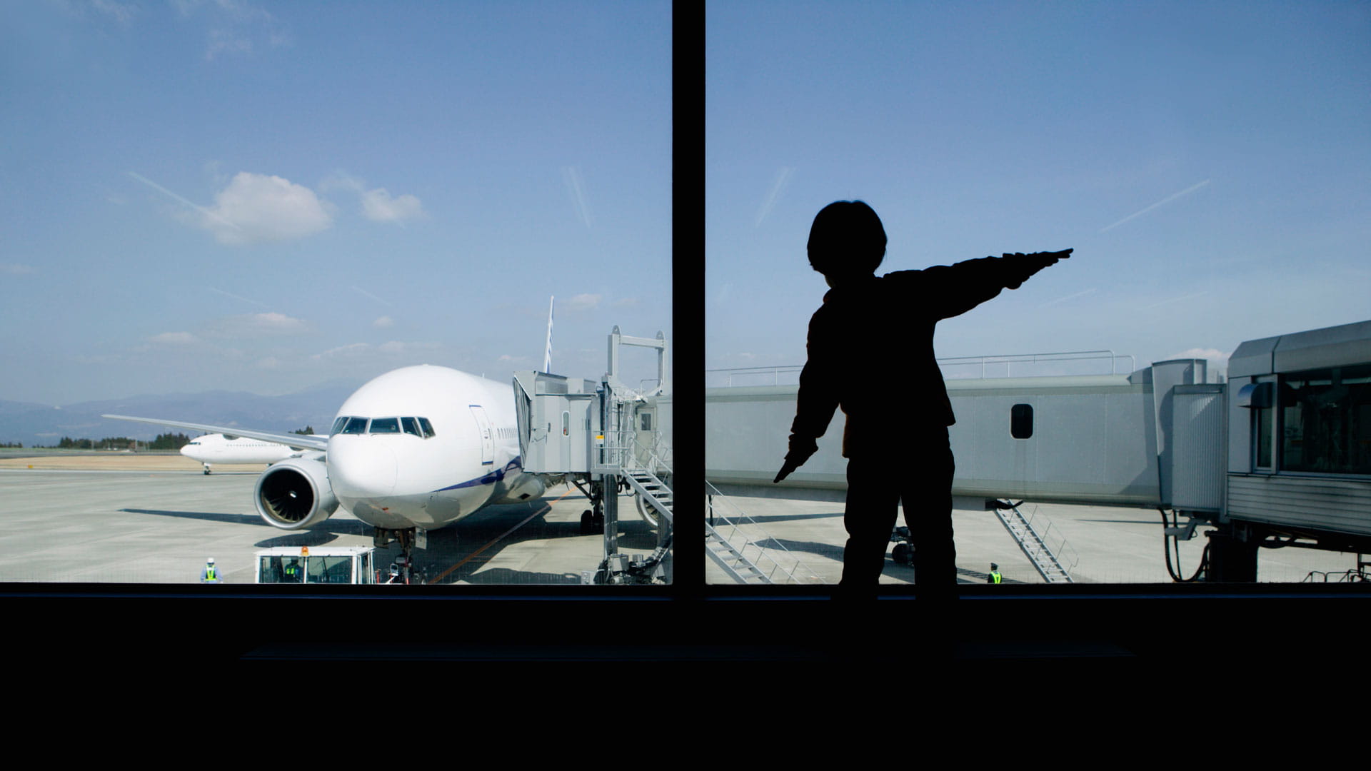 Child looking out an airport terminal at an airplane