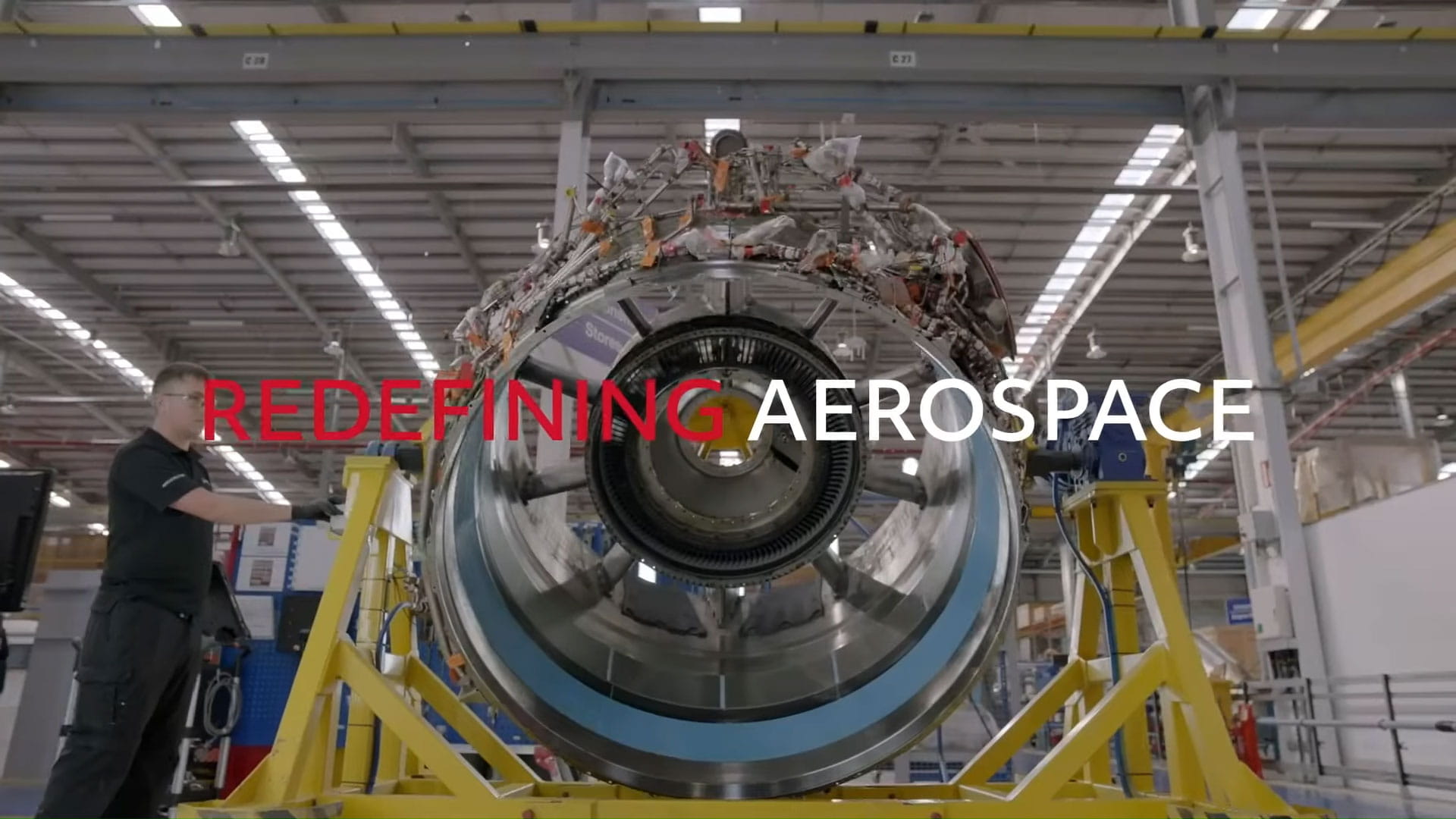 A technician works on a large piece of machinery. The text 'Redefining Aerospace' overlays the image.
