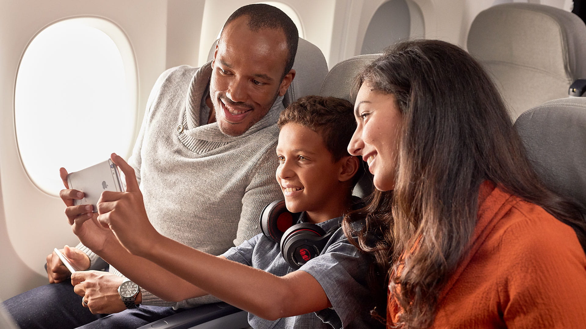 A family takes a selfie while sitting in an aircraft