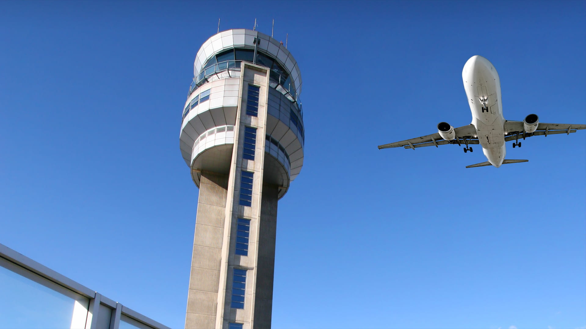 An aircraft flies over an ir traffic control tower