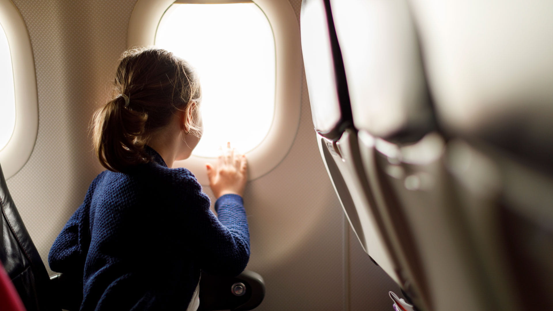 A girl looks out the window of an airplane