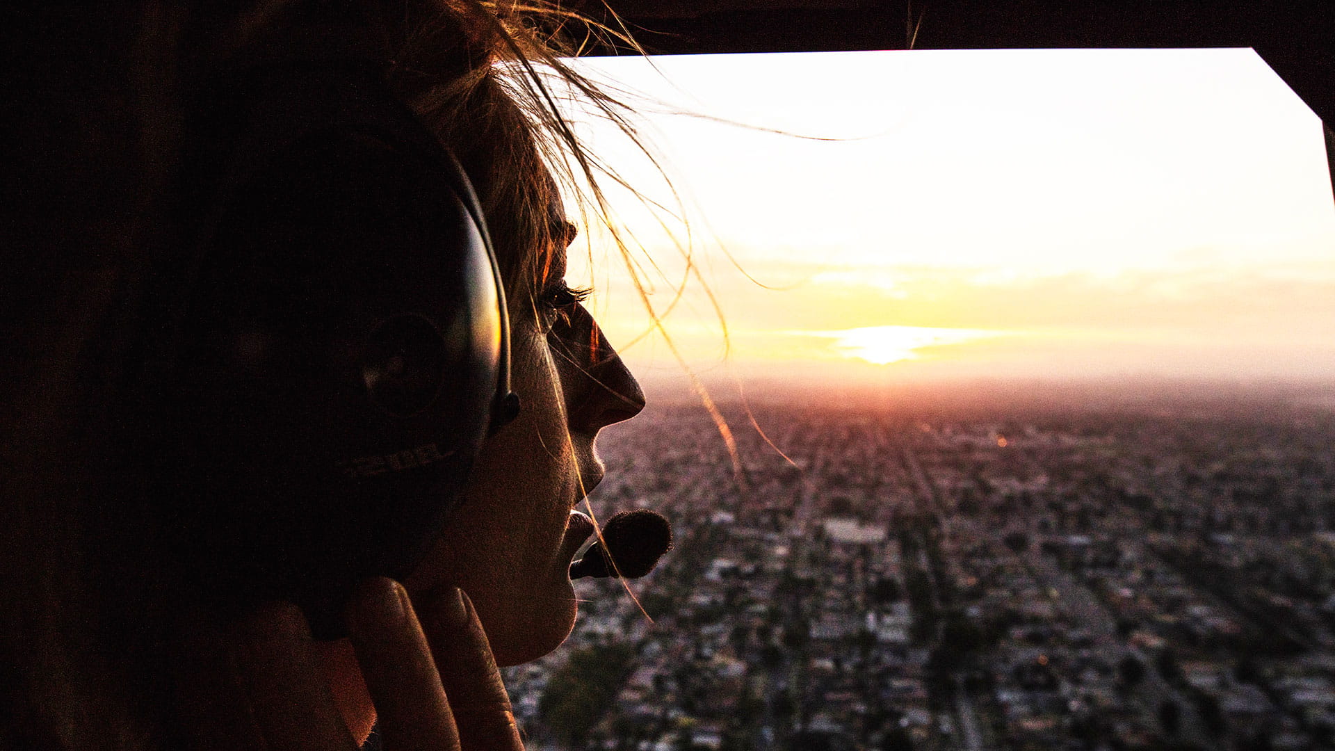 Woman looking out of aircraft into the sunset