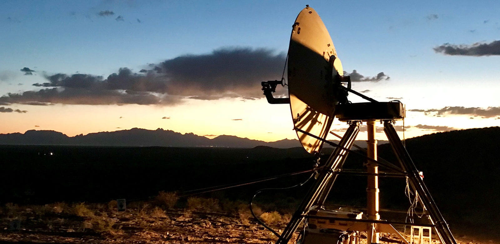 Troposcatter radar in the sunset, pointing over uneven terrain