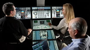 Three people sitting in an aircraft cockpit simulator