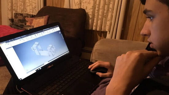 Alex Enes, a Mount Hope student in the Raytheon Missiles & Defense Stand and Deliver virtual mentoring program in Rhode Island, reviews mechanical drawings for his high school robotics team.