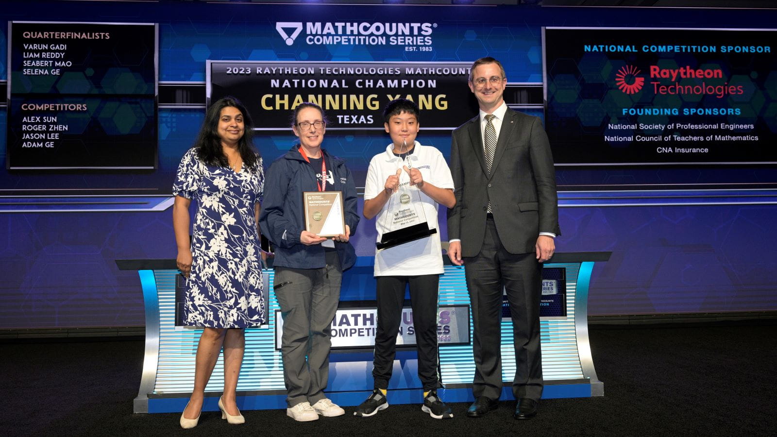 Channing Yang is presented with the 2023 Raytheon Technologies National Champion award by Bindu Nair, the director of basic research at the Office of the Under Secretary of Defense, his coach Andrea Smith, and Tracey Gray, MATHCOUNTS board chair and vice president of Communications and External Affairs for Raytheon Intelligence & Space.