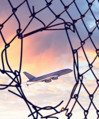 A plane taking off, seen through a hole in the fence