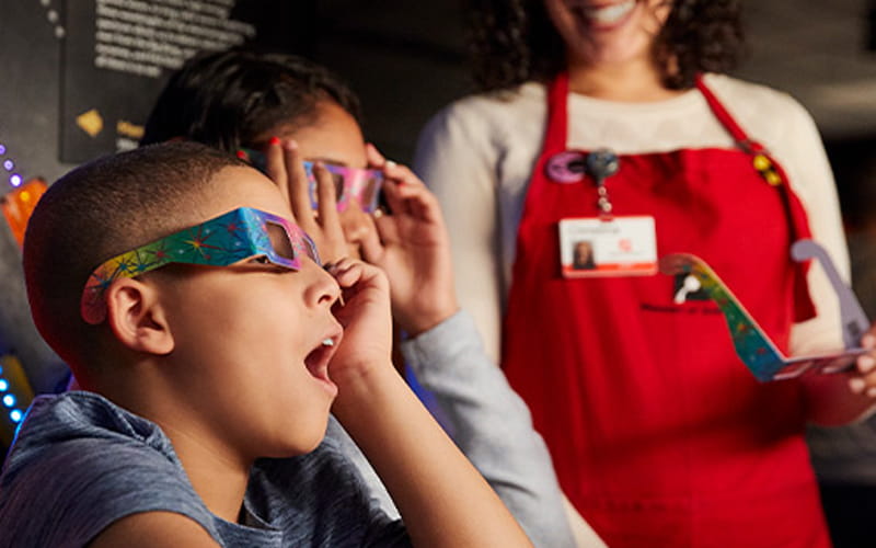 Children trying on special glasses at an exhibit at the Museum of Science