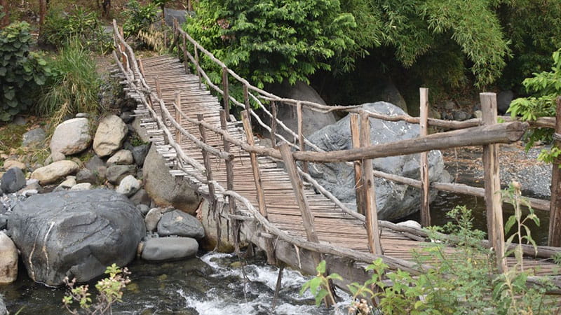 The original pedestrian bridge experiences seasonal flooding that move large rocks downstream. 